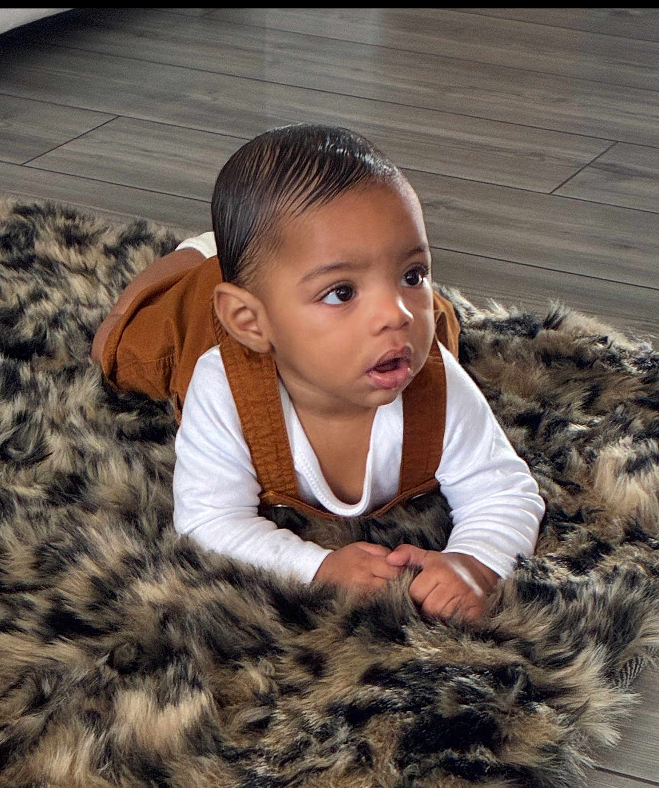 Yuriye joined the competition — help win amazing prizes! baby, brown_overalls, child, clothing, curious, expression, eyes, face, flooring, fur_rug, hair, hands, head, indoor, infant, lying_down, portrait, skin, white_shirt, young_child
