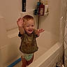 Axil is registered to the contest to win money with this photo: toddler, child, bathtub, bathroom, diaper, tshirt, smiling, standing, toilet_paper, shampoo_bottle, floor, bathroom_rack, curtain, tile_floor, playful, happy, indoor, person, young_child, home
