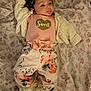 Braelynn is registered to the contest to win money with this photo: baby, infant, child, face, headband, clothing, sweater, floral_pattern, blanket, lying_down, cute, soft_lighting, portrait, indoors, person, baby_clothes, head, expression, comfortable, young