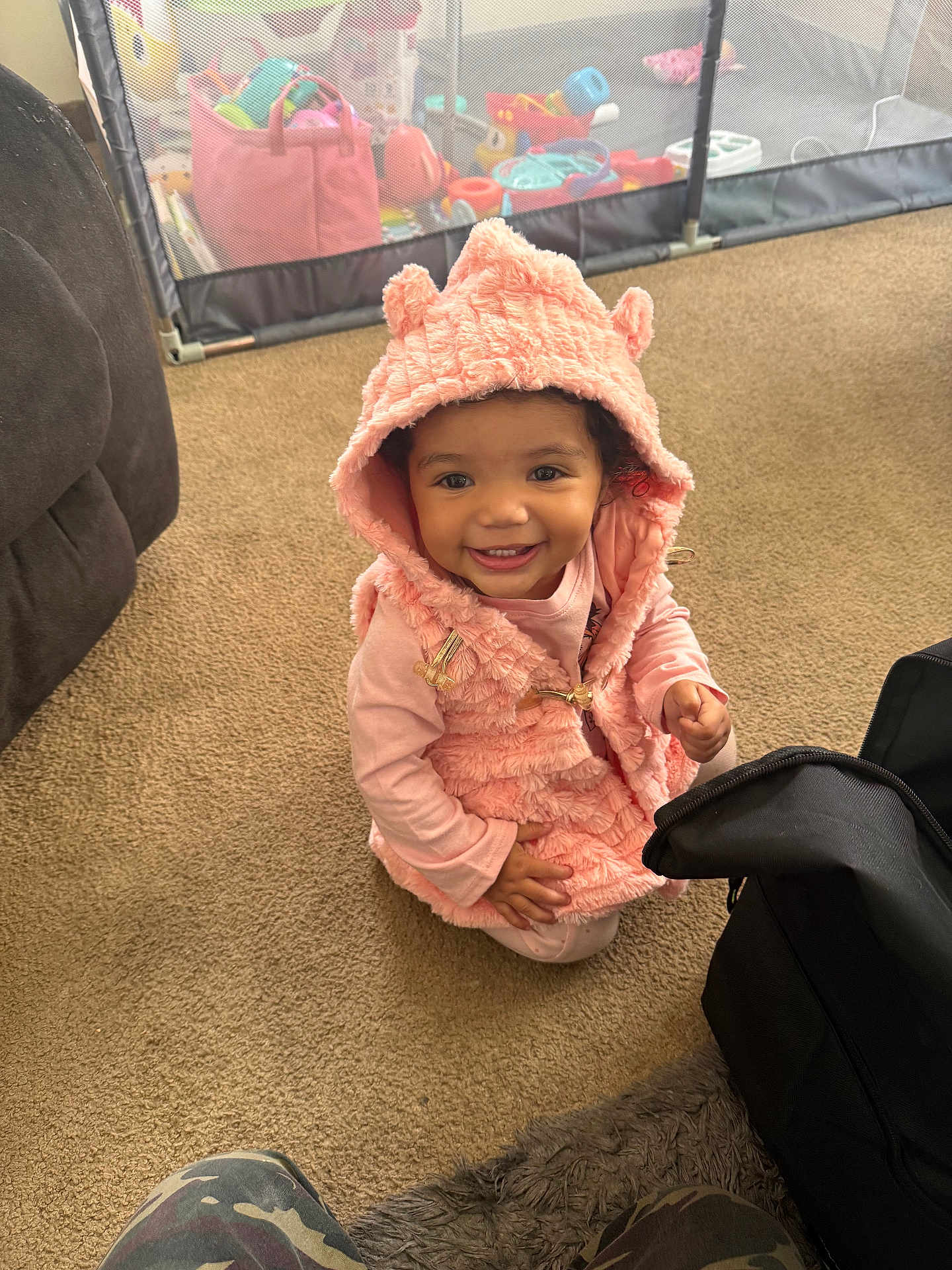 Braelynn joined the competition — help win amazing prizes! toddler, child, smile, pink_clothing, hooded_vest, carpet, indoor, playpen, toys, happy, person, baby, candid, cute, floor, young_child, warm_clothing, home, black_bag, casual
