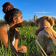 Avana participe au concours pour gagner de l'argent avec cette photo : woman, dog, golden_retriever, grass, outdoor, sunlight, blue_sky, bandana, nature, pet, casual_clothing, bracelet, earrings, tattoo, side_profile, summer, relaxation, friendship, field, sunset