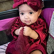Octavia is registered to the contest to win money with this photo: baby, infant, child, red_dress, headband, bow, stroller, tulle, sparkle, cute, chubby_cheeks, clothing, portrait, indoor, hand, face, person, sitting, expression, comfort