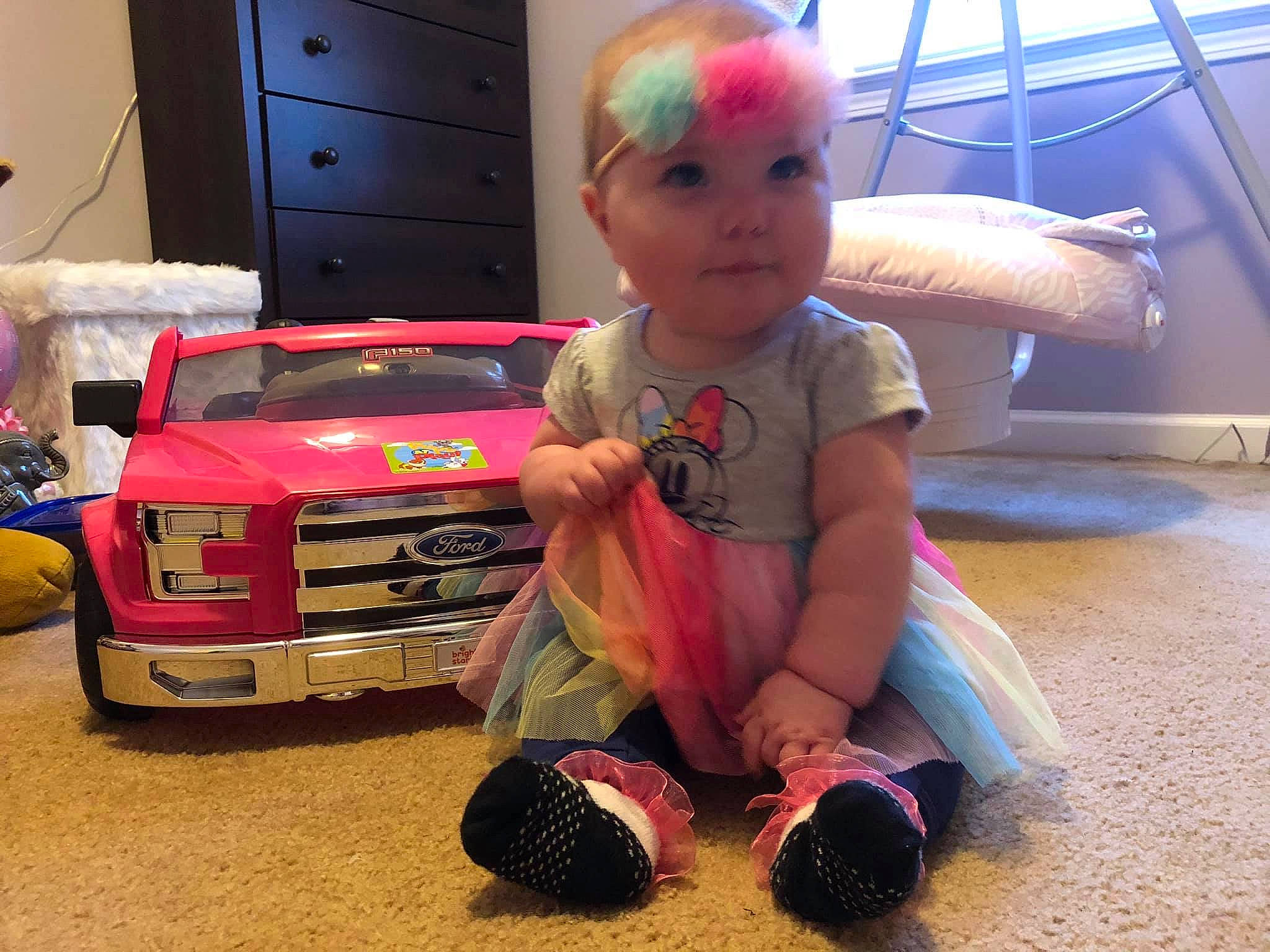 Silvia is registered to the contest to win money with this photo: car, child, floor, flooring, fun, headwear, person, pink, play, sport_utility_vehicle, stuffed_toy, toddler, toy, toy_vehicle, vacation, vehicle