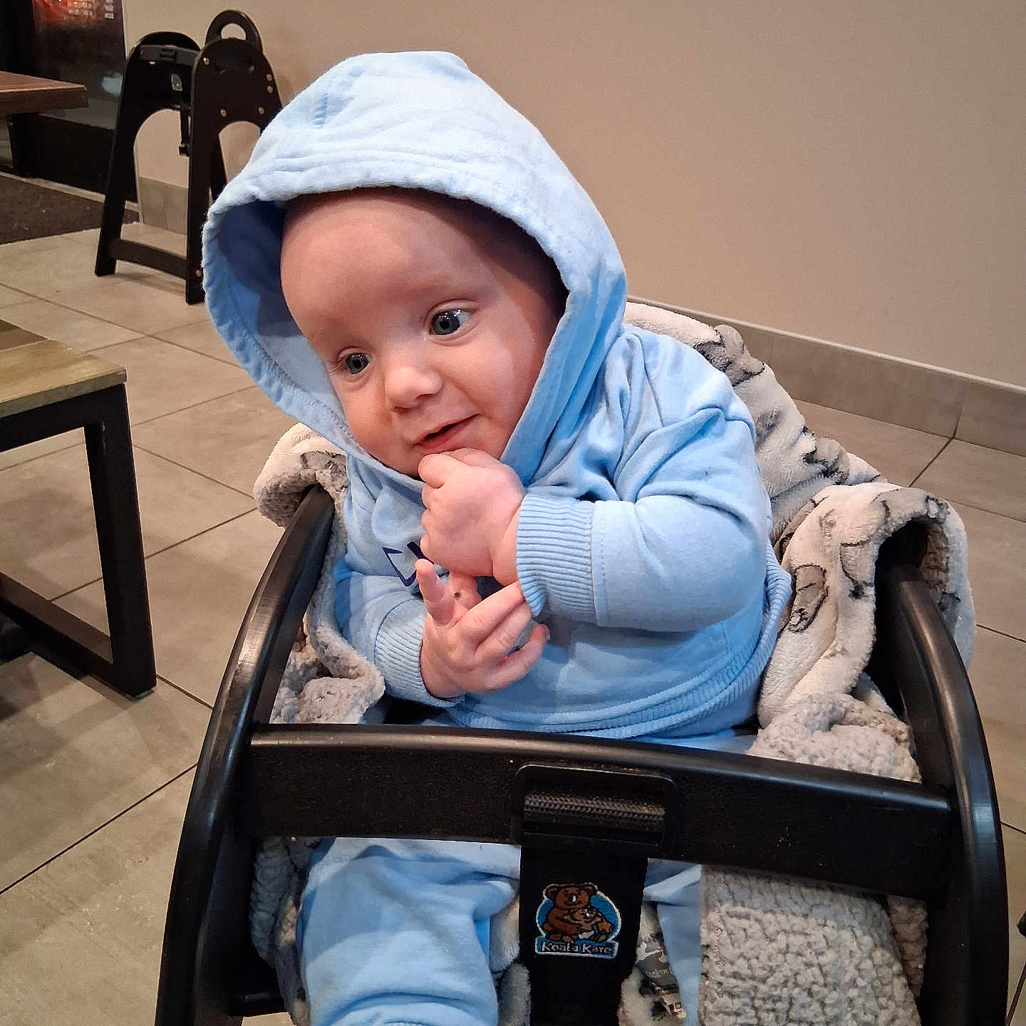Baby Bobby is registered to the contest to win money with this photo: baby, bonnet, chair, clothing, coat, face, furniture, hat, head, hood, hoodie, jacket, knitwear, pants, person, photography, portrait, sitting, sweater, sweatshirt