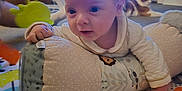 Archie joined the competition — help win amazing prizes! baby, infant, pillow, play_mat, cat, television, woman, living_room, floor, toy, colorful, curious, face, hand, clothing, indoor, carpet, smile, person, couch
