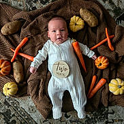 Jasper joined the competition — help win amazing prizes! baby, infant, blanket, carrot, potato, pumpkin, white_onesie, knitted_blanket, floor, cute, lying_down, two_months, autumn, vegetables, orange, yellow, brown, cozy, indoors, portrait