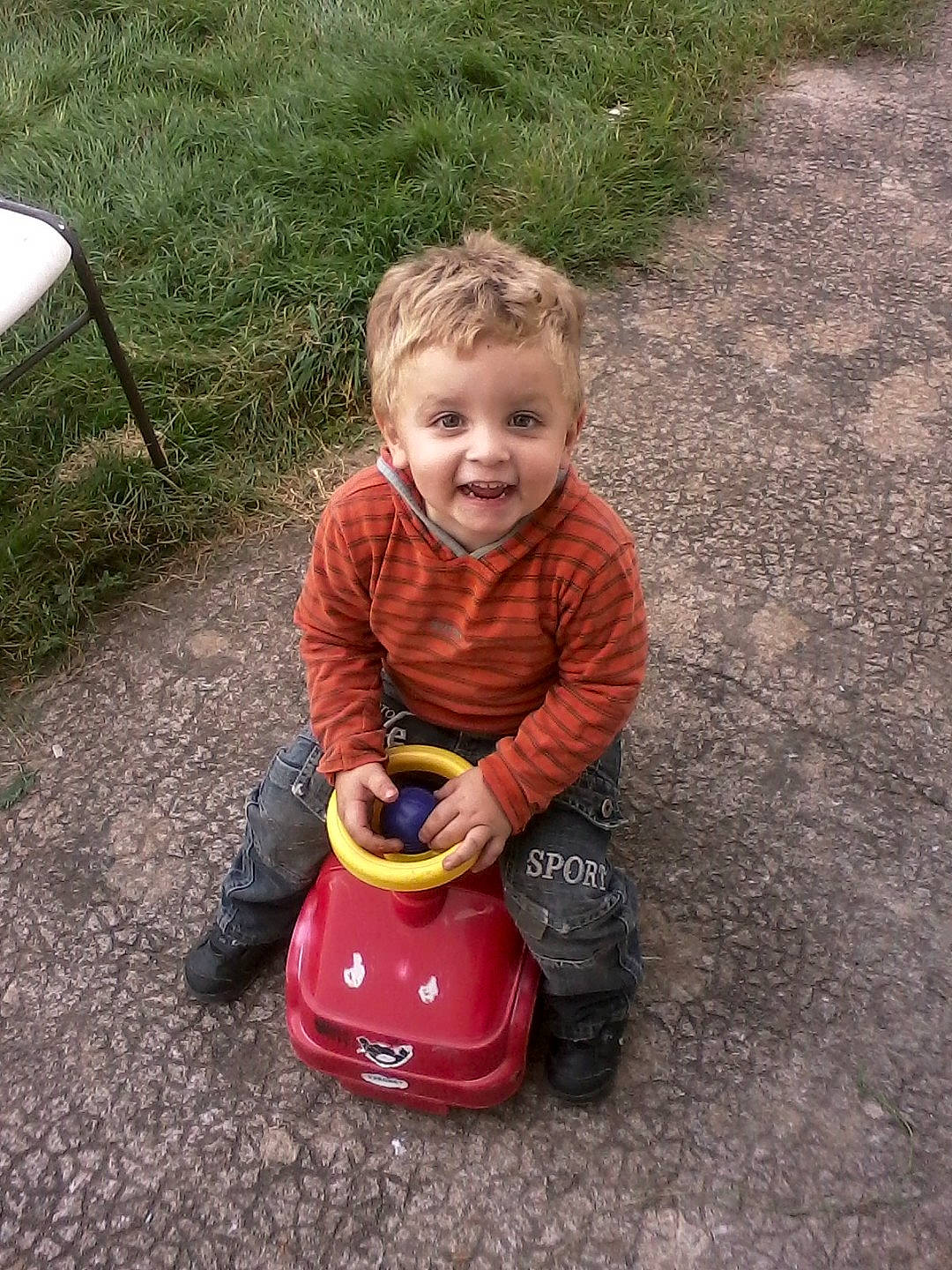 Lukas participe au concours pour gagner de l'argent avec cette photo : asphalt, baby, baby_toddler_clothing, child, fun, grass, happy, outdoor_furniture, people_in_nature, person, play, recreation, road_surface, sitting, smile, soil, toddler, toy, yard