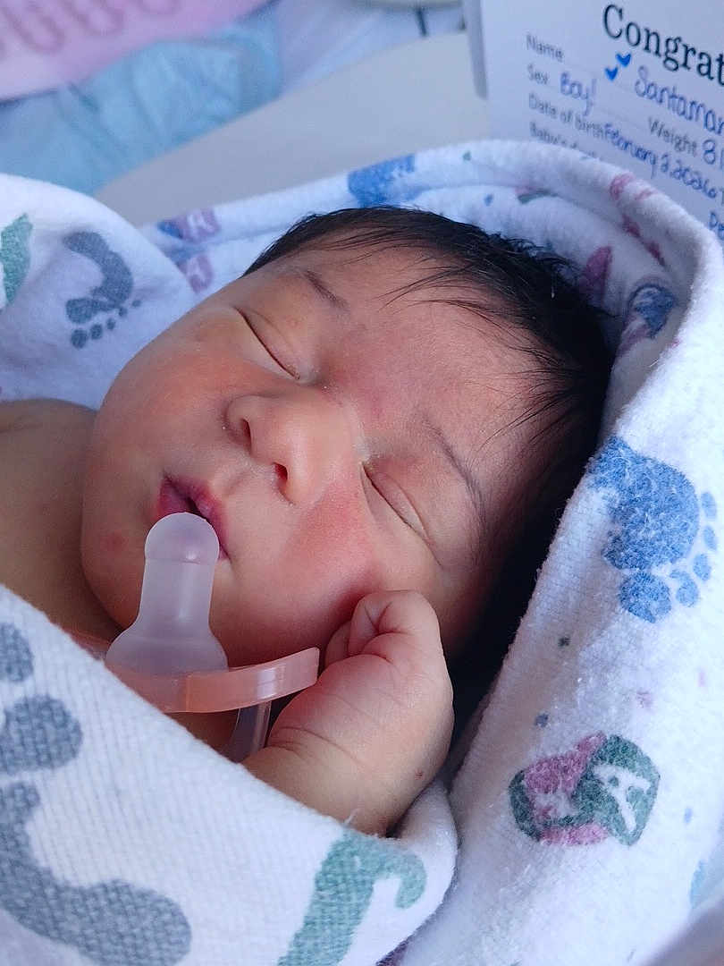 Brycen is registered to the contest to win money with this photo: baby, newborn, infant, pacifier, swaddle, blanket, sleeping, portrait, close_up, hospital, hospital_blanket, hand, face, hair, cheek, tiny_fingers, peaceful, cozy, congratulations_card, newborn_bassinet