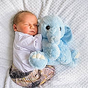 Morgan is registered to the contest to win money with this photo: baby, bed, blue_elephant, clothing, cozy, cuddle, indoor, infant, infant_clothing, newborn, nursery, peaceful, plush_toy, portrait, sleeping, small_child, soft_texture, stuffed_elephant, top_view, white_blanket