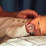 Violet is registered to the contest to win money with this photo: newborn, baby, pacifier, hand, blanket, infant, sleeping, closeup, soft_lighting, striped_clothing, bed, resting, skin, adult_hand, comfort, gentle, portrait, indoors, peaceful, tender