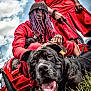 Doltch participe au concours pour gagner de l'argent avec cette photo : dog, person, purple_hair, beanie, red_clothing, black_dog, car, outdoor, grass, leash, tongue_out, close_up, portrait, smiling, vibrant_colors, dreadlocks, sky, urban, street_style, accessories