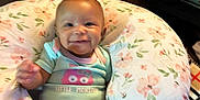 Mo Zyiah is registered to the contest to win money with this photo: baby, smiling, onesie, floral_pillow, couch, blanket, infant, happy, child, indoor, cute, comfort, nursing_pillow, person, apparel, pattern, face, seated, home, soft