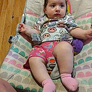 Harley is registered to the contest to win money with this photo: baby, child, infant, baby_seat, colorful_clothing, pink_socks, plush_toy, wooden_floor, smiley_face, curly_hair, cute, indoors, seat_belt, comfort, casual, expression, relaxed, portrait, person, young