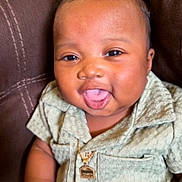 Jaliq is registered to the contest to win money with this photo: baby, brown_furniture, buttoned_shirt, child, couch, curly_hair, cute, face, green_clothing, hand, happy, indoors, infant, necklace, portrait, sitting, skin, smiling, tongue_out, young_child