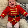 baby, child, costume, red_uniform, gold_trim, hat, boots, smiling, happy, indoor, blanket, couch, cute, portrait, infant, fuzzy_background, clothing, person, sitting, funny