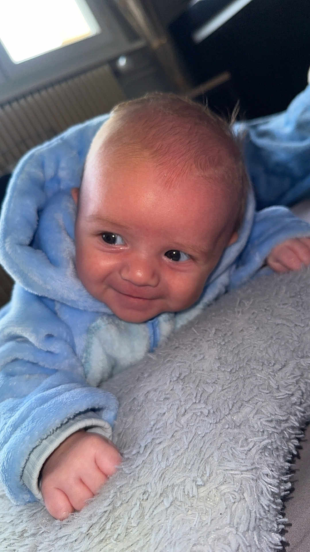 Timéo a rejoint le concours — aidez-le/la à gagner de superbes lots ! baby, infant, blue_onesie, blanket, smiling, face, hand, indoor, cozy, cute, child, soft_texture, portrait, newborn, happy, lying_down, expression, person, warm, window