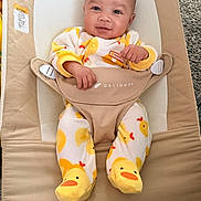Javari joined the competition — help win amazing prizes! baby, baby_bouncer, beige, bouncer, carpet, cute, duck_pattern, duck_slippers, fabric, feet, hands, indoor, infant, legs, onesie, portrait, safety_strap, seat, smile, yellow
