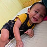 baby, child, smiling, denim_overalls, yellow_shirt, bed, pillow, indoor, happy, cute, infant, person, skin, head, face, hand, leg, red_socks, cozy, portrait