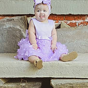 Ellianna joined the competition — help win amazing prizes! baby, child, infant, portrait, sitting, smiling, tongue_out, lavender_dress, bow, hair_accessory, gold_shoes, outdoor, stone_steps, brick_wall, house_exterior, full_body, cute, fashion, happy, photography