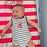 baby, infant, child, smiling, patriotic, american_flag, fourth_of_july, red_white_blue, striped_outfit, hat, flower_arrangement, booties, lying_down, portrait, indoor, celebration, holiday, playmat, happy, photography