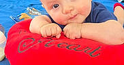 Liam Alexander joined the competition — help win amazing prizes! baby, blue_bedding, blue_shirt, child, close_up, curious, cushion, face, home, indoor, infant, lying_down, photography, portrait, red_clothing, red_cushion, short_hair, sitting, smiling, toy