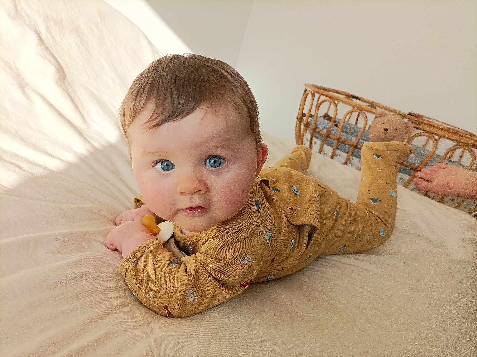 Lilio a rejoint le concours — aidez-le/la à gagner de superbes lots ! baby, blue_eyes, onesie, bed, tummy, wicker_crib, teddy_bear, foot, soft_lighting, curious_expression, animal_prints, indoor, child, infant, blanket, cozy, person, cute, home, sleepwear