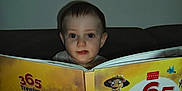 Loris participe au concours pour gagner de l'argent avec cette photo : animal_book, book, child, colorful, couch, curious, dark_background, expression, eyes, face, furniture, indoor, learning, literature, person, portrait, reading, storybook, toddler, young