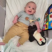 Louis a rejoint le concours — aidez-le/la à gagner de superbes lots ! baby, infant, smiling, toy, plush_toy, penguin, crib, blanket, clothing, pants, onesie, child, happy, face, person, indoor, colorful, soft, playful, cute