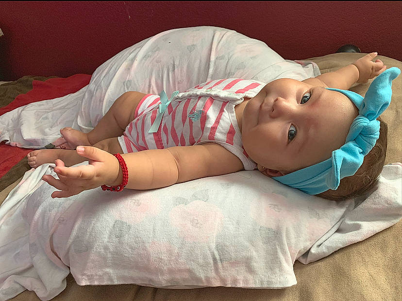 Galilea is registered to the contest to win money with this photo: arm, baby, beauty, bedding, cheek, child, eye, hand, happy, headwear, human, leg, linens, mouth, nose, person, photography, pillow, pink, skin
