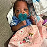 baby, infant, child, portrait, pacifier, couch, blanket, pink_blanket, blue_shirt, sitting, lying_down, wide_eyes, indoors, living_room, household, textile, cartoon, minnie_mouse, cozy, close_up