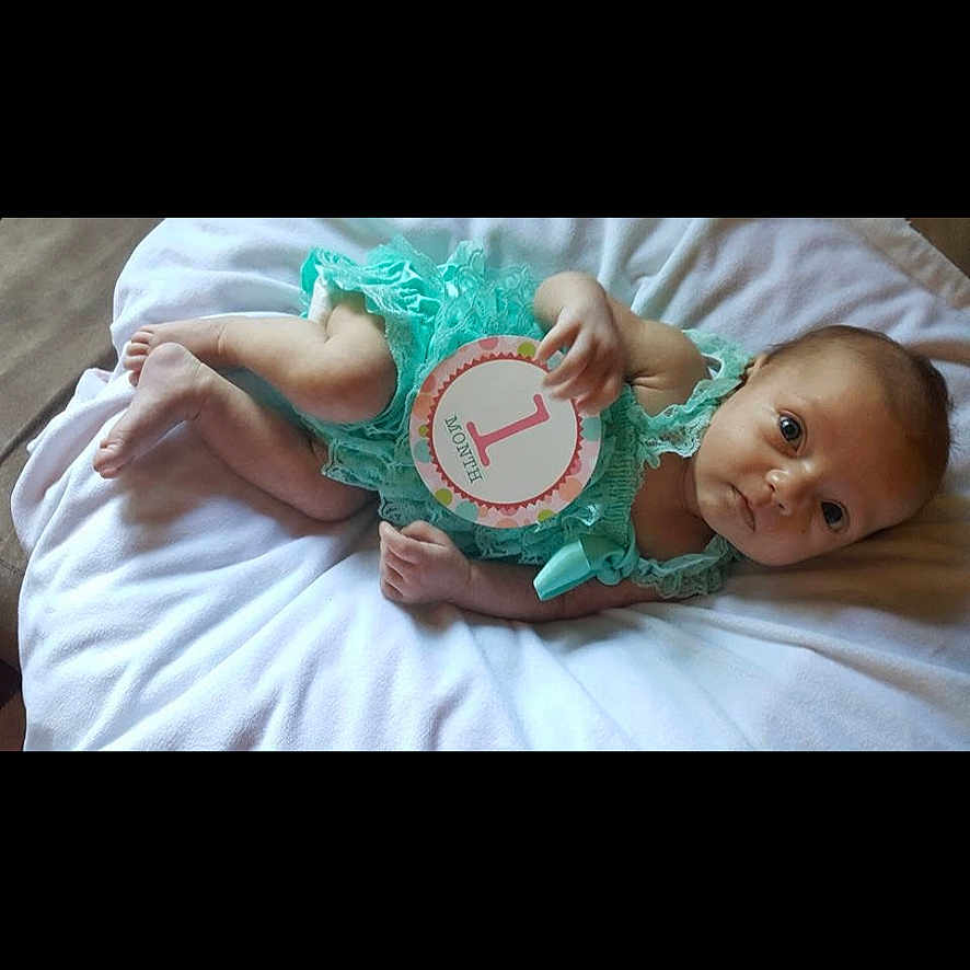 Kenley joined the competition — help win amazing prizes! baby, bed, blanket, child, clothing, cute, face, hand, indoors, infant, lying_down, milestone, newborn, one_month, person, portrait, resting, sign, skin, young