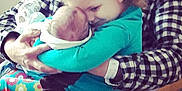 Jayden is registered to the contest to win money with this photo: child, baby, hugging, love, family, indoor, person, adult, checkered_shirt, bow, teal_clothing, newborn, affection, closeup, seated, caring, tender, human, portrait, parent