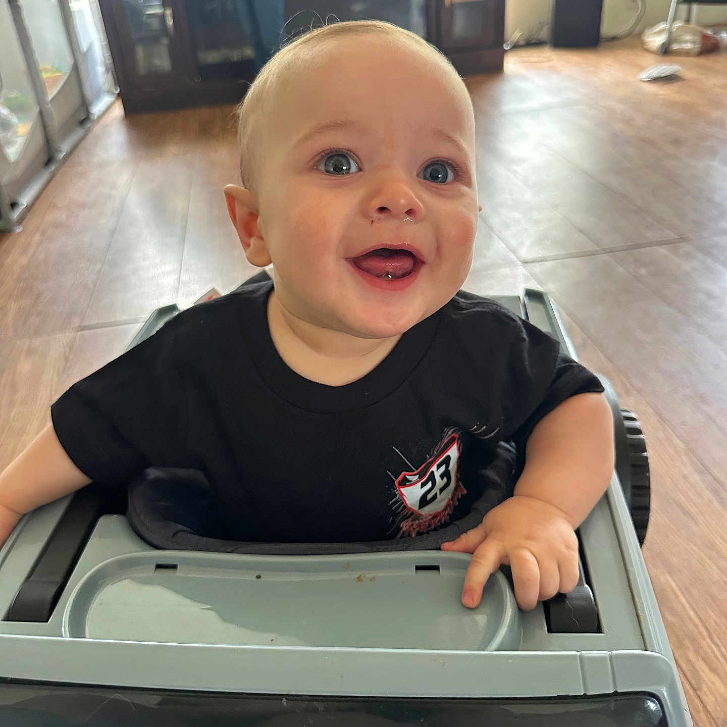 Mattaeo joined the competition — help win amazing prizes! adult, baby, black_shirt, blurred_background, cabinet, child, drool, face, flooring, furniture, hand, happy, indoor, light, person, shirt, smiling, toy_car, window, wood_floor