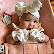 Isabella joined the competition — help win amazing prizes! baby, infant, mittens, headband, bow, babybjorn, carrier, pink, clothing, cute, face, portrait, child, seated, indoor, soft, adorable, young, expression, closeup