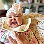 Isabella joined the competition — help win amazing prizes! baby, smiling, headband, flower, hand, chair, rainbow_pattern, bib, clothing, infant, happy, portrait, sitting, indoor, person, cute, child, apparel, candid, toddler