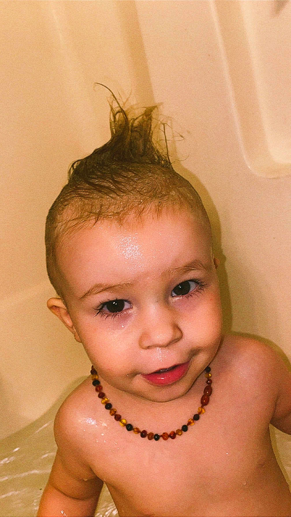 Sebastian joined the competition — help win amazing prizes! toddler, child, bathtub, water, wet_hair, mohawk, necklace, beads, smiling, face, skin, indoors, bath, cute, playful, young_child, portrait, head, shoulders, happy