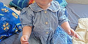 Aria participe au concours pour gagner de l'argent avec cette photo : baby, child, smiling, blue_eyes, headband, bow, dress, blue_dress, checkered, bed, pillow, blanket, indoor, cute, happy, seated, person, infant, skin, foot