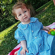 Aria a rejoint le concours — aidez-le/la à gagner de superbes lots ! baby, child, blue_eyes, blue_dress, gingham_pattern, toy, blanket, outdoor, grass, tree, nature, sunlight, playtime, cute, portrait, sitting, person, smile, greenery, daylight