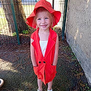 Giulia a rejoint le concours — aidez-le/la à gagner de superbes lots ! child, concrete_wall, fashion, feet, fence, girl, grass, happy, nature, orange_hat, orange_vest, outdoor, person, playground, smile, summer_clothing, sunlight, tree, white_sandals, young