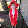 Giulia a rejoint le concours — aidez-le/la à gagner de superbes lots ! child, concrete_wall, fashion, feet, fence, girl, grass, happy, nature, orange_hat, orange_vest, outdoor, person, portrait, smile, standing, summer_clothing, sunlight, tree, white_sandals