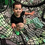 active, beige_pants, black_shirt, candid, child, curly_hair, cute, foam_blocks, fun, green_socks, happy, indoor, leisure, net, person, play_area, playground, rope, smiling, toddler