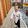 beams, casual_clothing, child, daylight, happy, indoor, modern_interior, person, playful, portrait, pullover, railing, smiling, stone_floor, toddler, walking, white_sneakers, window, wooden_floor, young_child