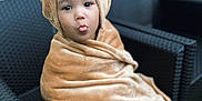 Issa participe au concours pour gagner de l'argent avec cette photo : bear_hood, blanket, child, cozy, cute, expression, face, furniture, fuzzy, indoors, kid, playful, portrait, sitting, smile, soft, tongue_out, wicker_chair, wrapped, young_child