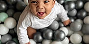 Zakariya a rejoint le concours — aidez-le/la à gagner de superbes lots ! baby, ball_pit, balls, black_balls, child, cute, face, fun, gray_balls, happy, indoor, infant, joyful, mint_green_balls, playful, portrait, sitting, smiling, white_clothing, young_child