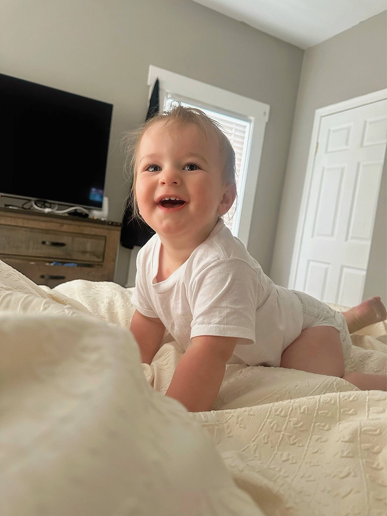 Adonis is registered to the contest to win money with this photo: baby, baby_toddler_clothing, bed, bed_sheet, bedding, child, comfort, computer_keyboard, computer_monitor, door, flooring, joy, linens, person, room, sitting, sleeve, smile, standing, television