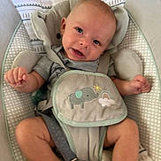 Grayson is registered to the contest to win money with this photo: baby, infant, baby_seat, cushion, harness, elephant_design, rainbow, clothing, smiling, face, legs, arms, indoor, fabric, pattern, comfort, child, cute, expression, seat