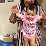 Augustina joined the competition — help win amazing prizes! baby, child, elderly_woman, great_grandma, smiling, indoor, family, holding_hands, pink_onesie, toys, basket, portrait, wooden_floor, striped_shirt, remote_control, wall_photos, happy, standing, person, home