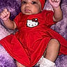 Anari is registered to the contest to win money with this photo: baby, infant, child, red_dress, headband, hello_kitty, purple_blanket, socks, cute, portrait, indoors, smiling, fist, soft_texture, cozy, person, newborn, fashion, happy, resting
