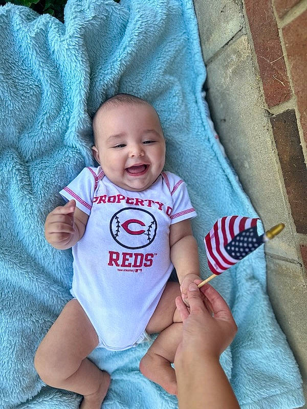 Kyson is registered to the contest to win money with this photo: arm, azure, baby, baby_toddler_clothing, child, cool, eye, facial_expression, finger, gesture, hand, happy, joy, organ, person, product, skin, sleeve, smile, t_shirt