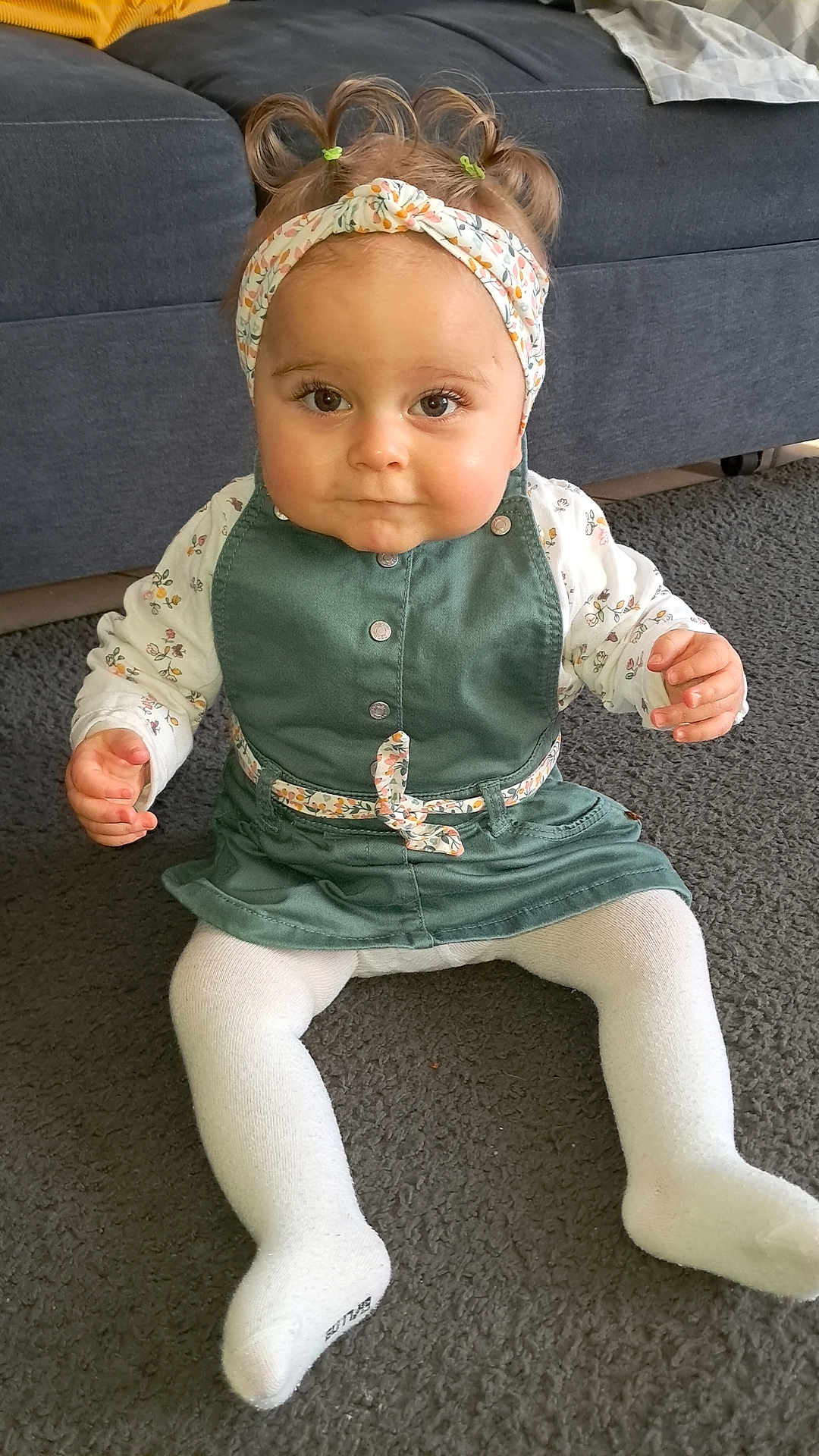 Thya a rejoint le concours — aidez-le/la à gagner de superbes lots ! child, baby, infant, toddler, headband, pigtails, dress, tights, sitting, carpet, sofa, indoor, portrait, big_eyes, cute, hands, buttons, floral_pattern, floor, smile
